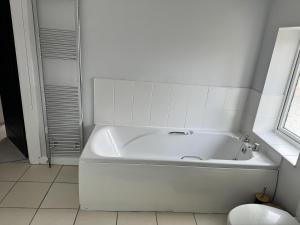 a white bath tub in a white bathroom at Impeccable 3-Bed House in Walsall in Walsall