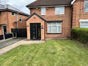 a brick house with a door and a grass yard at Impeccable 3-Bed House in Walsall in Walsall