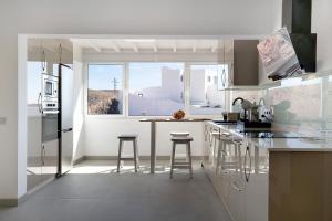 a white kitchen with a counter and stools at Casa Mara 2 in Playa Quemada