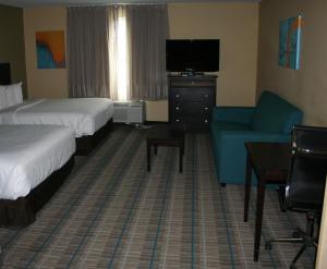 ein Hotelzimmer mit 2 Betten, einem TV und einem Sofa in der Unterkunft MainStay Suites Jacksonville near Camp Lejeune in Jacksonville