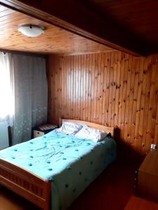 łóżko w pokoju z drewnianą ścianą w obiekcie Apartament na wsi w Lubniewicach