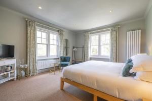 a bedroom with a bed and a tv and windows at Flower Pot Hotel in Henley on Thames