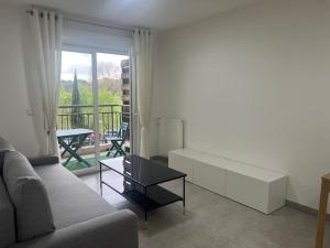 sala de estar con sofá, mesa y balcón en Le Vienna en Juvignac