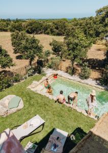 a group of people sitting in a swimming pool at Residence CASE DI PI GNA, deux magnifiques villas indépendantes avec piscines individuelles , proches de la plage d'Algajola in Algajola