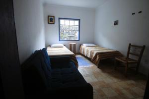 a room with two beds and a couch and a window at Casazul - OP in Ouro Preto