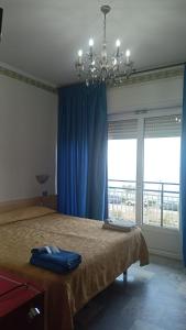 a bedroom with a bed with blue curtains and a chandelier at B&B Solana in Noli