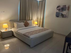 a bedroom with a large bed with two tables and two lamps at SIRIUS TOWER in Juffair