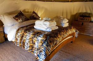 a bed with animal print sheets and towels on it at Burtree Country House and Retreats Tipi in Thirkleby