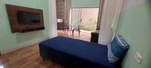 um quarto com uma cama azul e uma televisão em Apê Estúdio Tropical em Paranaíba
