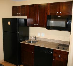 a kitchen with a black refrigerator and a sink at MainStay Suites Jacksonville near Camp Lejeune in Jacksonville +21 photos