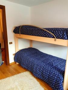 een slaapkamer met een stapelbed en een blauw dekbed bij Casa Dolce Presena in Passo del Tonale