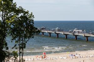 a pier over the beach with people in the water at Aquamarina Prima 07 Seaside Studio by the BEACH with Terrace by Renters in Międzyzdroje