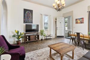 a living room with a tv and a table at 3BD HOME STEPS TO SAINT CHARLES Gated Parking in New Orleans
