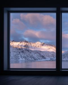 una ventana con vistas a una montaña nevada en Polar Panorama Lodge, en Fjordgård