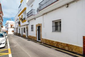una calle con edificios blancos y un coche aparcado en la calle en Aptº Jábega, Familias y Parejas, en Conil de la Frontera