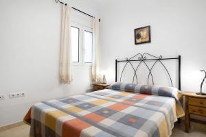 Un dormitorio con una cama con una manta a cuadros. en Aptº Jábega, Familias y Parejas, en Conil de la Frontera
