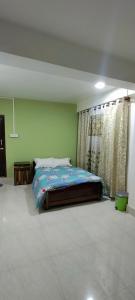 1 dormitorio con cama y pared verde en Gyatso Guest House en Tawang
