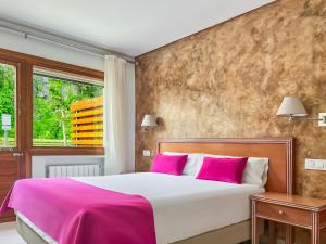 a bedroom with a large bed with pink pillows at Hotel Los Arces in Isla