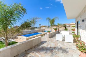un patio con 2 sillas blancas y una piscina en Villa Arjana, en Camemi