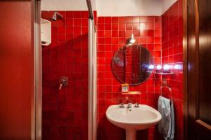 un bagno piastrellato rosso con lavandino e specchio di Modest & Cheap Tavern for a Spartan Retreat a Courmayeur