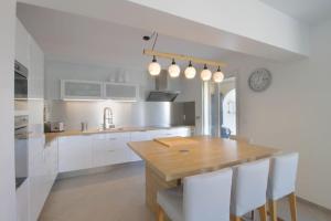 uma cozinha com uma mesa de madeira e armários brancos em Pretty terraced house with garden level and garage em Aix-les-Bains