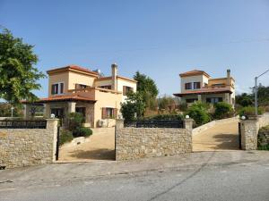 una casa con una valla de piedra frente a una entrada en Agnanti Marina villa with private pool, en Skouloúfia