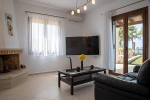 a living room with a couch and a tv at Agnanti Marina villa with private pool in Skouloúfia