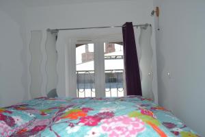- un lit avec une couette à fleurs devant une fenêtre dans l'établissement Je jazz les couleurs à Albi, Mon-Appart Hotel-ALBI, à Albi