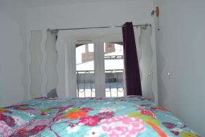 a bed with a floral comforter in front of a window at Je jazz les couleurs à Albi, Mon-Appart Hotel-ALBI in Albi