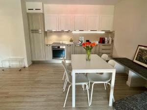 a kitchen with a white table and chairs and a table with flowers at Ascona: ORTO DEGLI ANGIOLI in Ascona +25 photos
