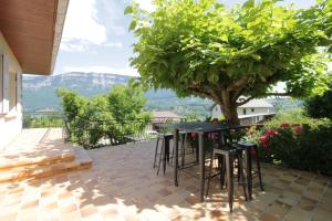 un patio con mesa y sillas bajo un árbol en Beautiful villa on the slopes of Lake Aiguebelette! en Saint-Alban-de-Montbel