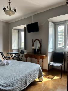 a bedroom with a bed and a table and a mirror at Residência Aviz in Peniche