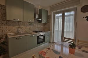 een keuken met groene kasten en een tafel met een eetkamer bij NONNA GENEROSA APARTMENTS in Castellammare di Stabia