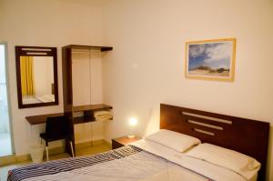 ein Schlafzimmer mit einem Bett, einem Spiegel und einem Stuhl in der Unterkunft Hostal Oro Negro in Talara