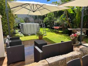 um pátio com um guarda-sol, cadeiras e uma mesa em Appartamento esclusivo con giardino em Neviano