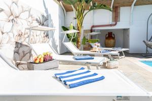 a group of white lounge chairs with towels on them at Villa Geraldina con piscina in Torre Suda