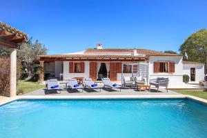 a pool with chairs and a table and a house at Villa Alegre in Pollença