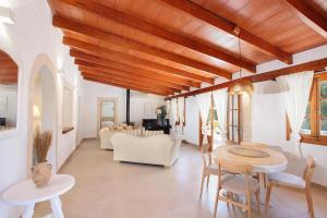 a living room with wooden ceilings and a table and chairs at Villa Alegre in Pollença