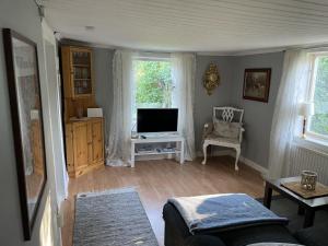 ein Wohnzimmer mit Sofa und Fernseher in der Unterkunft Genuine 100 year old countryside cottage in Rimbo