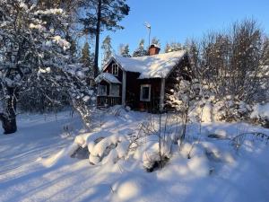 ein kleines Haus mit Schnee auf dem Dach in der Unterkunft Genuine 100 year old countryside cottage in Rimbo