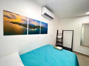 a room with a bed with a blue blanket on it at Mayara Hostal in El Zonte