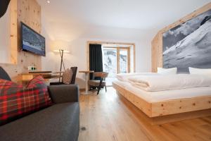 um quarto de hotel com uma cama, uma secretária e um sofá em Mondschein Hotel & Chalet em Stuben am Arlberg