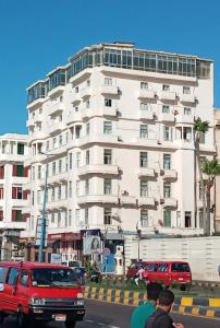 un gran edificio blanco con gente parada frente a él en Semiramis hotel, en Alejandría