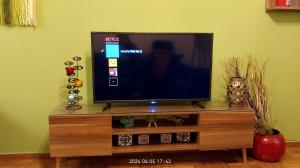 una TV a schermo piatto seduta sopra un centro di intrattenimento in legno di Anna's Flat No2- 2 bedroom apartment a Volos
