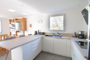 uma cozinha com armários brancos e um balcão de madeira em Pretty new and comfortable house between towns and lakes em Voglans
