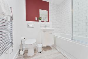 La salle de bains blanche est pourvue de toilettes et d'une baignoire. dans l'établissement Stunning 1 Bed Apartment Nightingale Quarter Derby, à Derby
