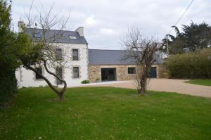 una gran casa blanca con un patio verde en Gîte de LANVIAN en Guissény