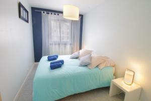 1 dormitorio con 1 cama con sábanas y almohadas azules en Comfortable T3 at the foot of the Castle of Chambéry! en Chambéry