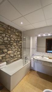 een badkamer met een stenen muur, een bad en een wastafel bij Hotel Casona Los Caballeros in Santillana del Mar