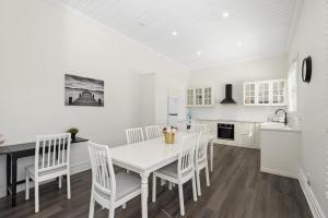 a white kitchen with a white table and chairs at Portia-Close to City Ctre Beach in Geelong